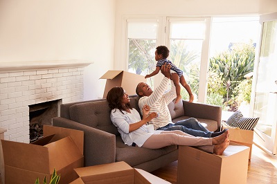 couple playing with baby surrounded by moving boxes
