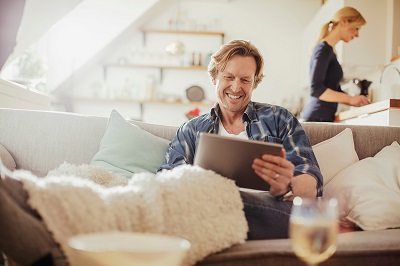 man using tablet on sofa