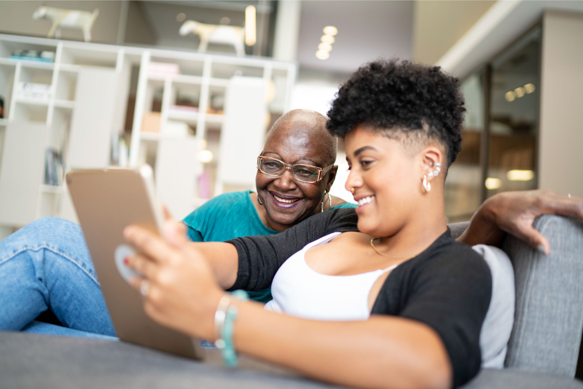 Pay Down Debt Blog - WOMAN WITH HER MOTHER LOOKING AT A TABLET ON THE COUCH